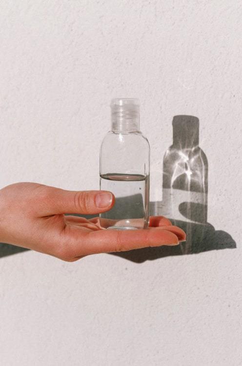 Hand holding clear bottle of disinfectant